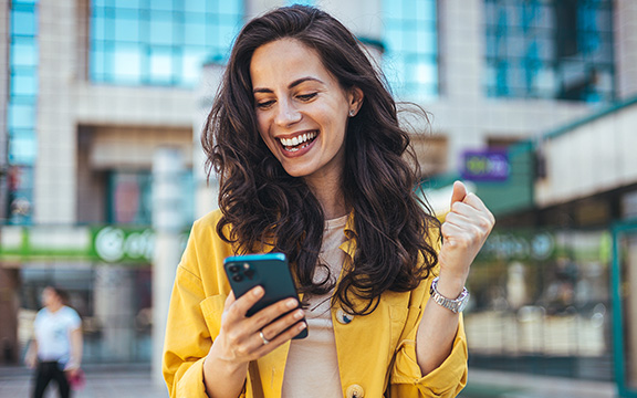 boldog telefonját néző mosolygó nő