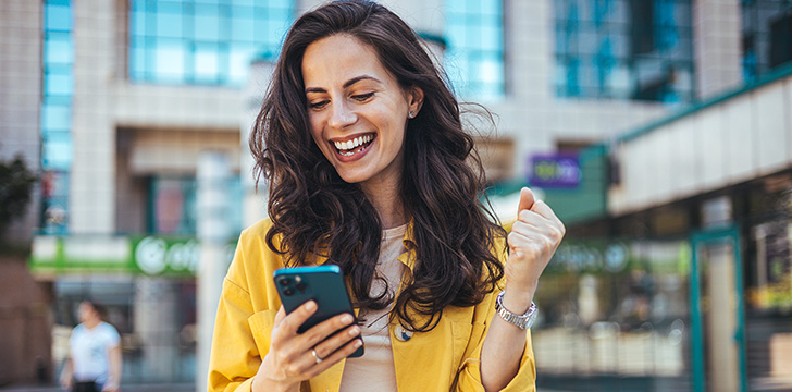 boldog telefonját néző mosolygó nő