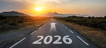 Egyenes országút ‘2026’ felirattal és előre mutató nyíllal naplementében.