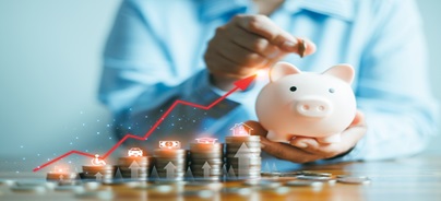 Egy kéz pénzt helyez egy malacperselybe, miközben érmékből képzett oszlopok előtt egy felfelé tartó piros nyíl jelenik meg a megtakarítások növekedését jelképezve.