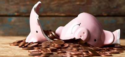 Egy összetört rózsaszín malacperselyből érmék szóródnak ki egy fa asztalra.