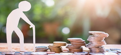 Papírfigura támaszkodik egy bottal érmékből álló oszlopok mellett, a nyugdíjcélú megtakarítások jelképeként.