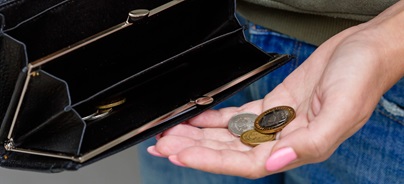 Egy család közösen tesz pénzt egy fehér perselymalacba az asztalnál, miközben a szülők a gyerekeknek mutatják a megtakarítás folyamatát.